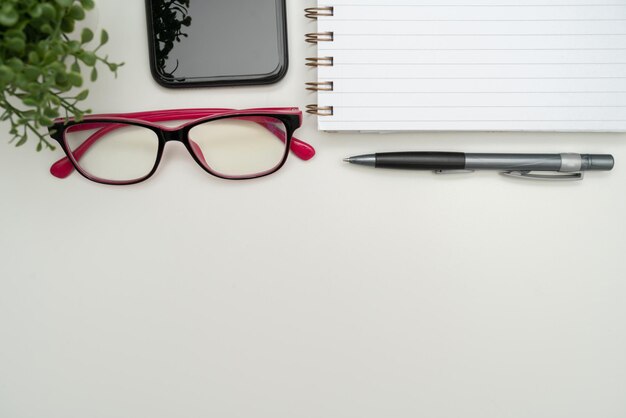 Fournitures de bureau sur bureau avec clavier et verres et tasse à café pour travailler à distance assorties