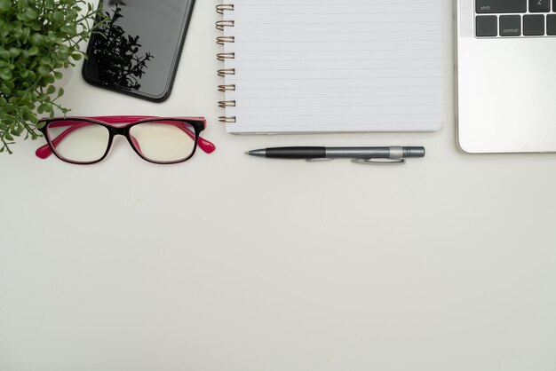 Fournitures de bureau sur bureau avec clavier et verres et tasse à café pour travailler à distance assorties