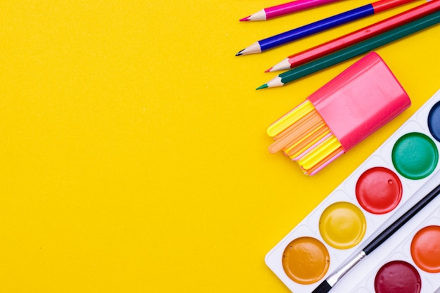 Fournitures de bureau sur fond jaune. Diverses fournitures scolaires sur une table jaune vif avec fond