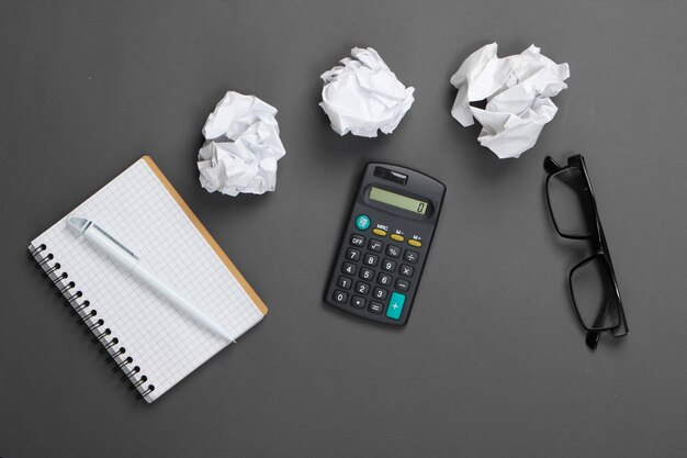 Fournitures de bureau sur un gris. Calculatrice, boules de papier froissé, cahier