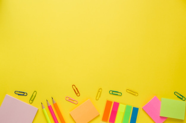 Fournitures de bureau sur une table jaune avec espace de copie.