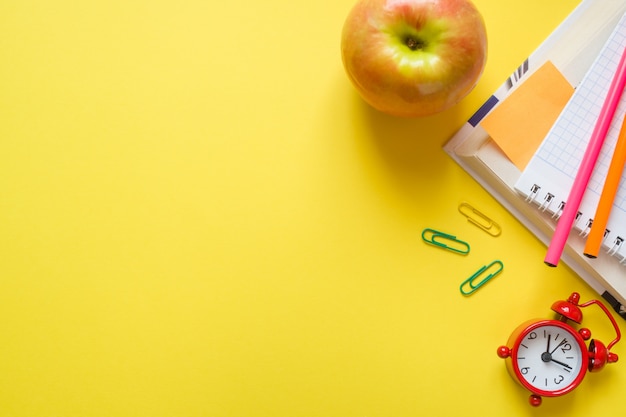 Fournitures de bureau sur une table jaune avec espace de copie.