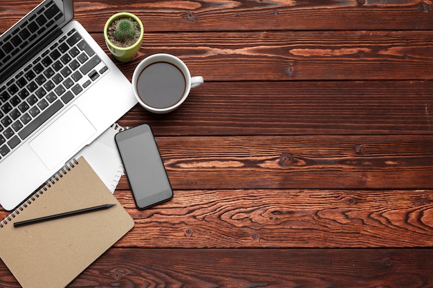 Fournitures et équipement de bureau sur une table en bois sombre, vue de dessus