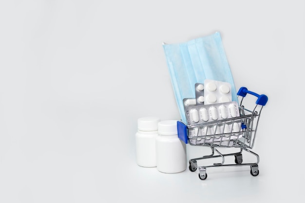 Les fournitures médicales de concept d'achat de médicaments sont dans un chariot de supermarché sur fond bleu