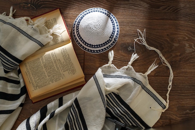 Fournitures de prière traditionnelles juives. Talite, kippa, torah sur une table en bois. Shabbatta, Bar Mitzvah, concept Yom Kippour