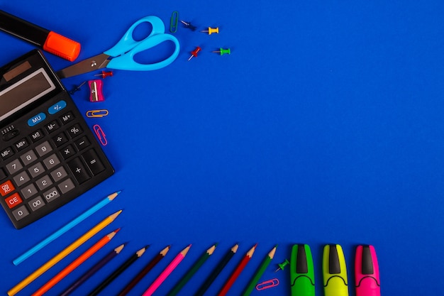 Fournitures scolaires ou de bureau sur fond bleu. Retour à l'école.