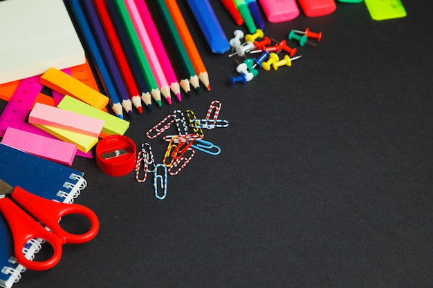 Fournitures scolaires et de bureau sur fond sombre. Vue de dessus avec espace copie