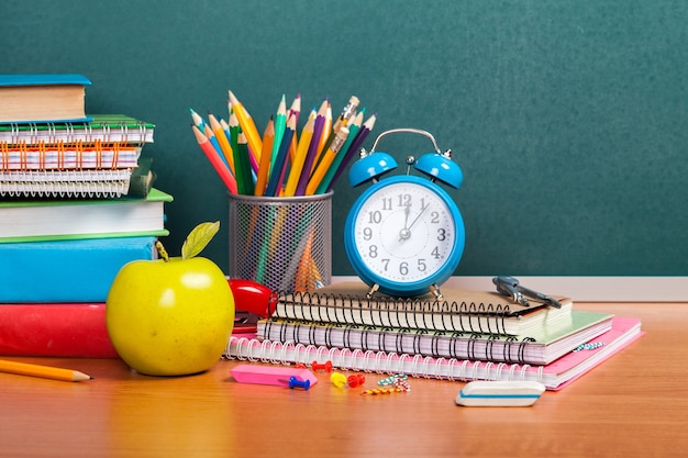 Fournitures scolaires colorées sur fond de tableau noir