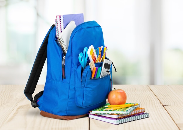 Fournitures scolaires colorées en sac à dos sur fond de tableau noir