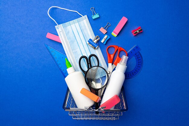 Fournitures scolaires dans un panier sur bleu