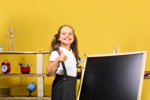 Fournitures scolaires et enfant sur fond de mur jaune