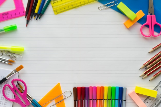 Fournitures scolaires sur une feuille dans un fond de règle