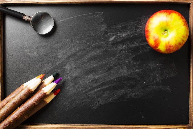 Fournitures scolaires sur fond noir. Disposition plate.