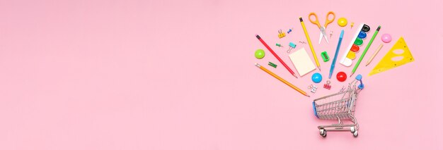 Fournitures scolaires sur fond rose dans le panier vue d'en haut bureau de l'espace de copie pour les étudiants...