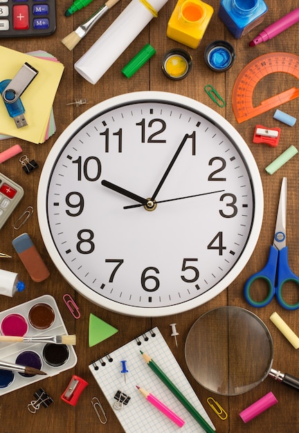 Photo fournitures scolaires et horloge sur table en bois