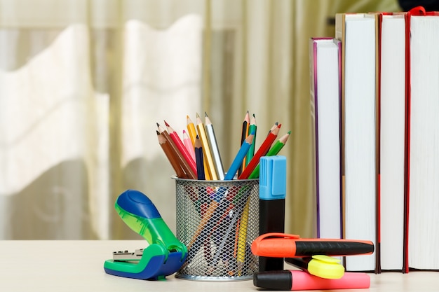 Fournitures scolaires. Livres, crayons de couleur, marqueurs, agrafeuse sur table en bois. Retour au concept de l'école