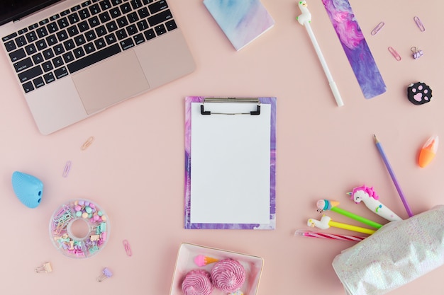 Fournitures scolaires avec un stylo licorne, un crayon lama et un ordinateur portable en rose.