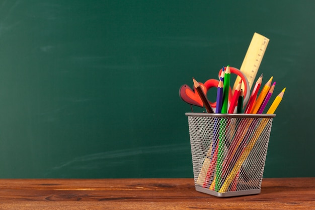 Fournitures scolaires sur une table en bois et tableau noir