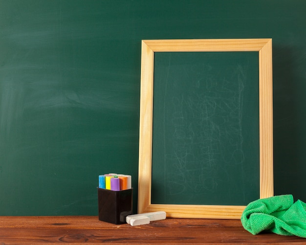 Fournitures scolaires sur une table en bois et tableau noir