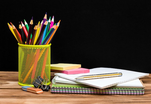 Fournitures scolaires sur table contre tableau noir Concept de l'éducation