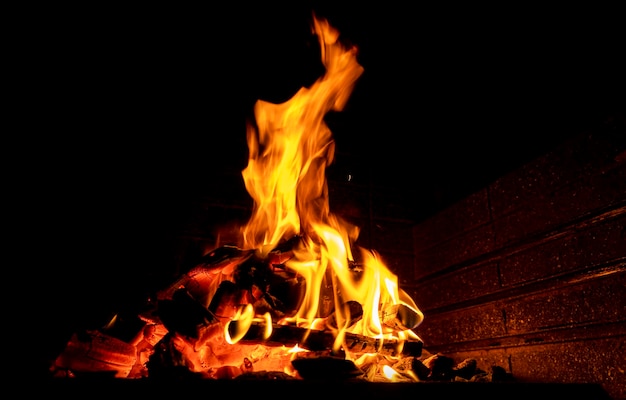 Foyer chaud plein de bois. De vraies flammes de fond de texture de bûches brûlantes. Fond de cheminée. La flamme du feu se bouchent.