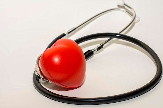 Foyer sélectif du stéthoscope sur une surface blanche avec un coeur rouge, concept médical