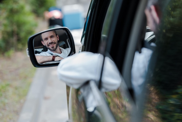 Foyer sélectif d'un homme joyeux regardant la fenêtre de la voiture et souriant dans la voiture