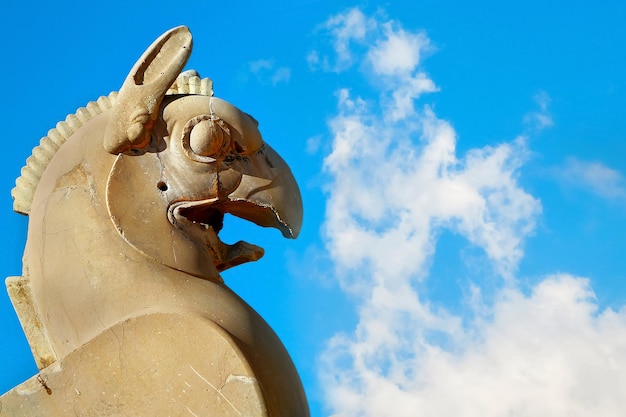 Fragment de colonne en pierre sculpture d'un griffon à Persépolis contre un ciel bleu avec des nuages ancien royaume achéménide Iran Perse Shiraz