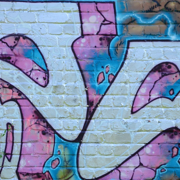 Fragment de dessins de graffitis Le vieux mur décoré de taches de peinture dans le style de la culture de l'art de la rue Texture de fond colorée dans des tons violets