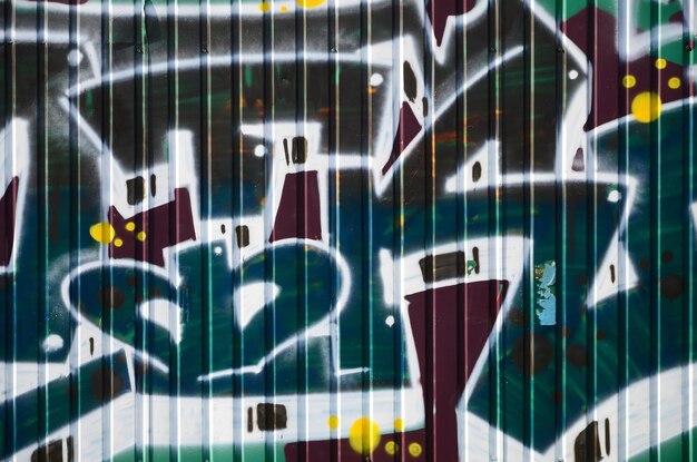Fragment de dessins de graffitis Le vieux mur décoré de taches de peinture dans le style de la culture de l'art de rue Texture de fond colorée en tons verts