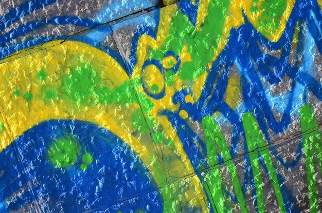 Photo fragment de dessins de graffitis le vieux mur décoré de taches de peinture dans le style de la culture de l'art de rue texture de fond colorée en tons verts
