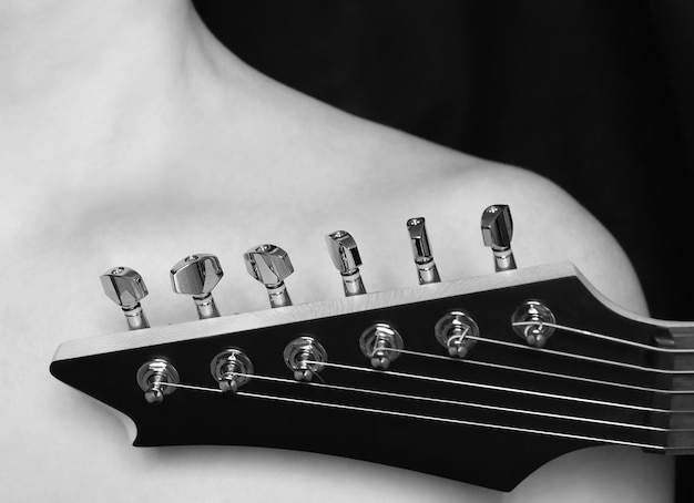 fragment d'une guitare électrique devant le corps féminin Esthétique de la lumière et de l'ombre musicale