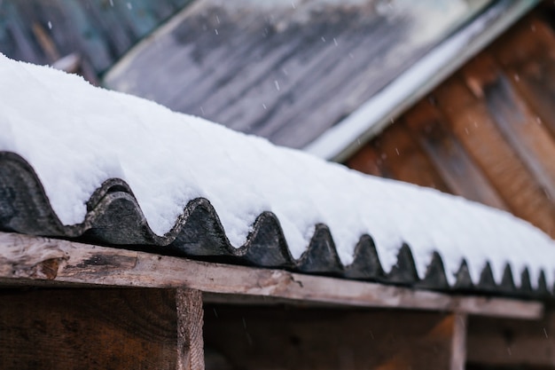 Photo fragment de toit en vieille ardoise ondulée, recouvert de neige blanche