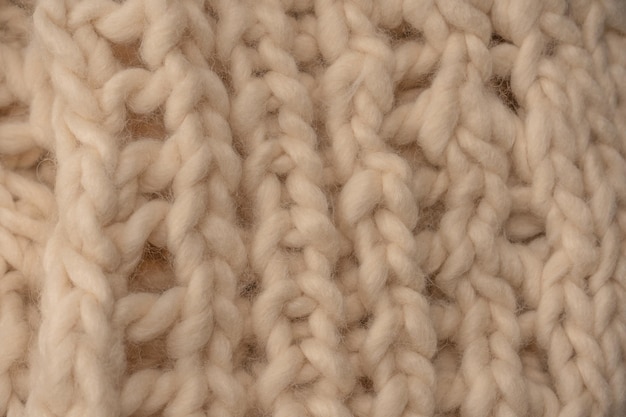 Un fragment de tricot beige tricoté à partir de laine de mouton blanche