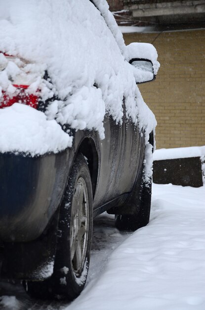 Fragment de la voiture sous une couche de neige après une forte chute de neige. Le corps de la voiture est recouvert de neige blanche