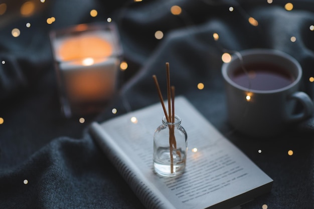 Fragrance liquide à la maison dans une bouteille en verre avec des bâtons en bois sur un livre en papier