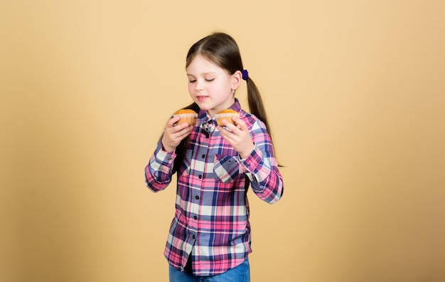 Fraîcheur de cuisson tous les jours Mignon petit enfant aime cuisiner et manger des aliments sucrés Adorable petite fille tenant des cupcakes fraîchement cuits Suivant la meilleure recette de cuisson Cuisson à la maison