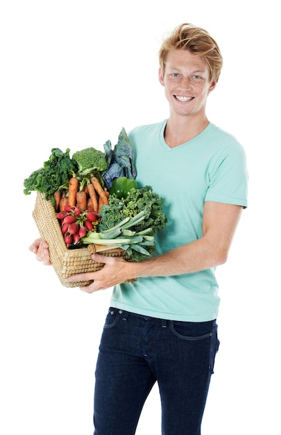 Frais de la ferme Un jeune homme roux souriant tenant un panier rempli de légumes biologiques frais