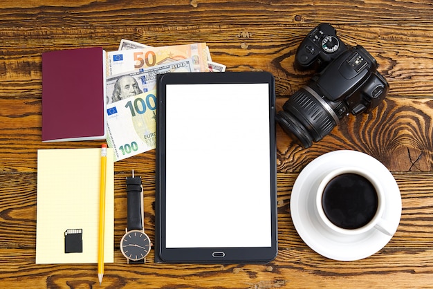 Photo frais généraux pour les jeunes modernes. différents objets sur table en bois. concept de voyage. passeport, appareil photo, argent, tablette, café