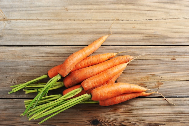 Frais jeunes carottes entières sur fond rustique en bois