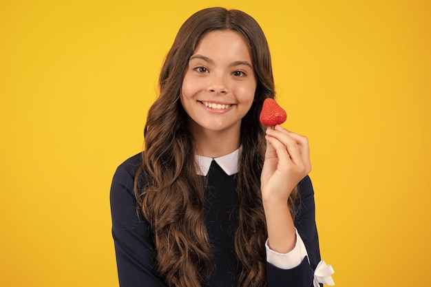 Fraise appétissante Portrait of cute teen girl eating fraises isoalted sur fond jaune