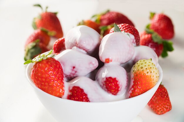 Fraise avec chantilly dans un bol blanc sur tableau blanc