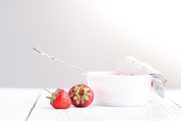 Fraise à la crème de lait sur un tableau blanc avec une cuillère à la main féminine