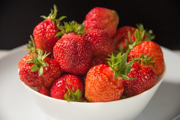 Fraise dans une assiette blanche close up sur fond noir