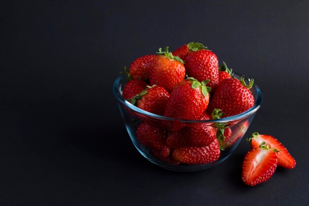 Fraise dans le bol en verre sur le fond noir Copier l'espaceCloseup