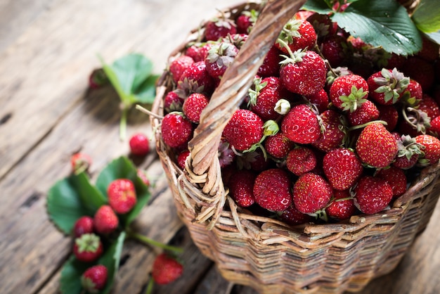 Fraise dans le panier avec des feuilles vertes sur bois