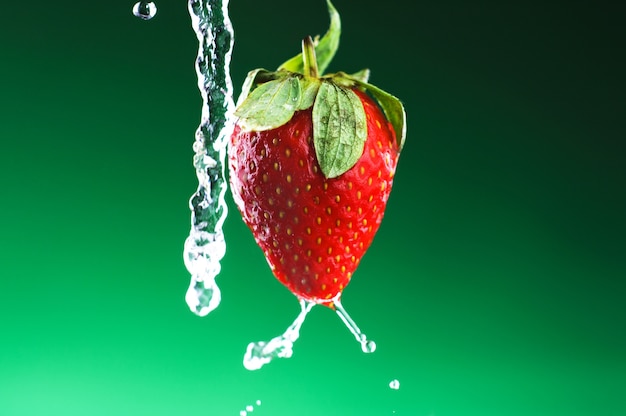 Fraise sur un fond vert avec des gouttes d&#39;eau