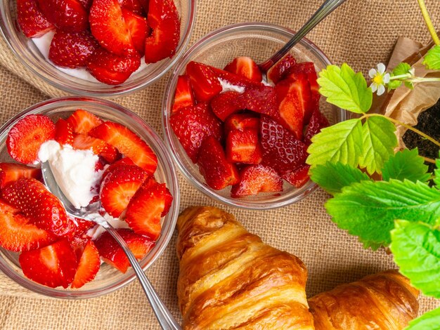 Fraise fraîche du jardin mûre avec de la crème et des croissants sur un gros plan d'un sac