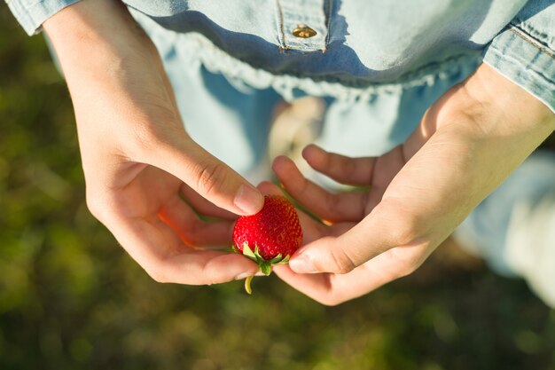 Une fraise à la main de la femme.