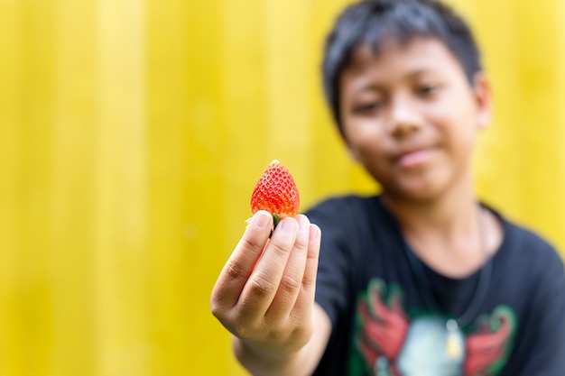 Fraise, main garçon, isolé, dans, jaune, fond